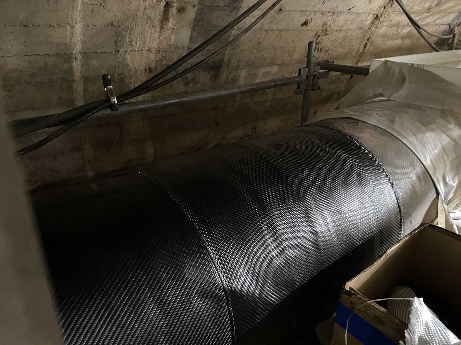 Technician applying a fibre-reinforced composite wrap to industrial pipework